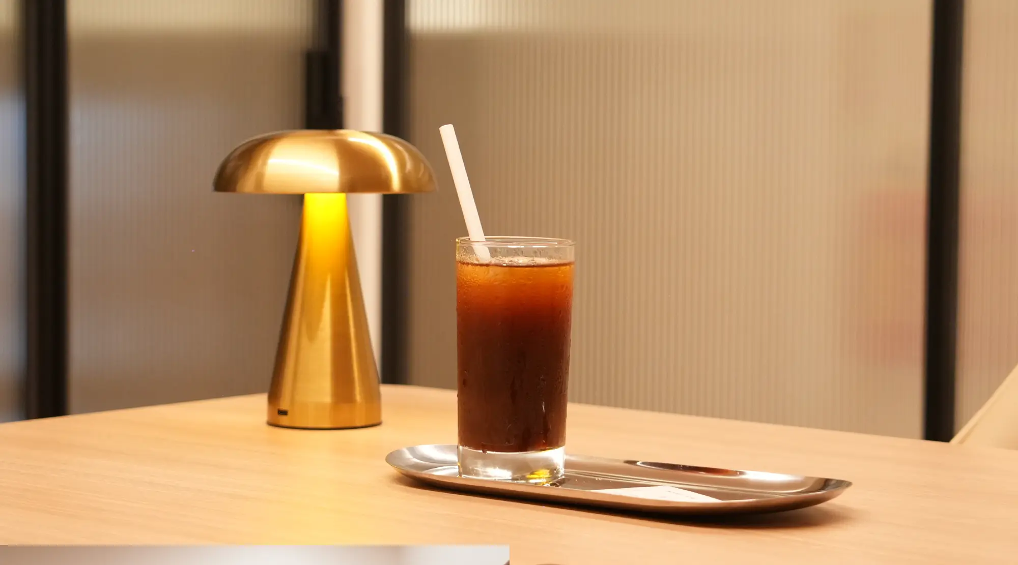 A warm lamp and iced coffee on a coworking table at Unlock Everyday