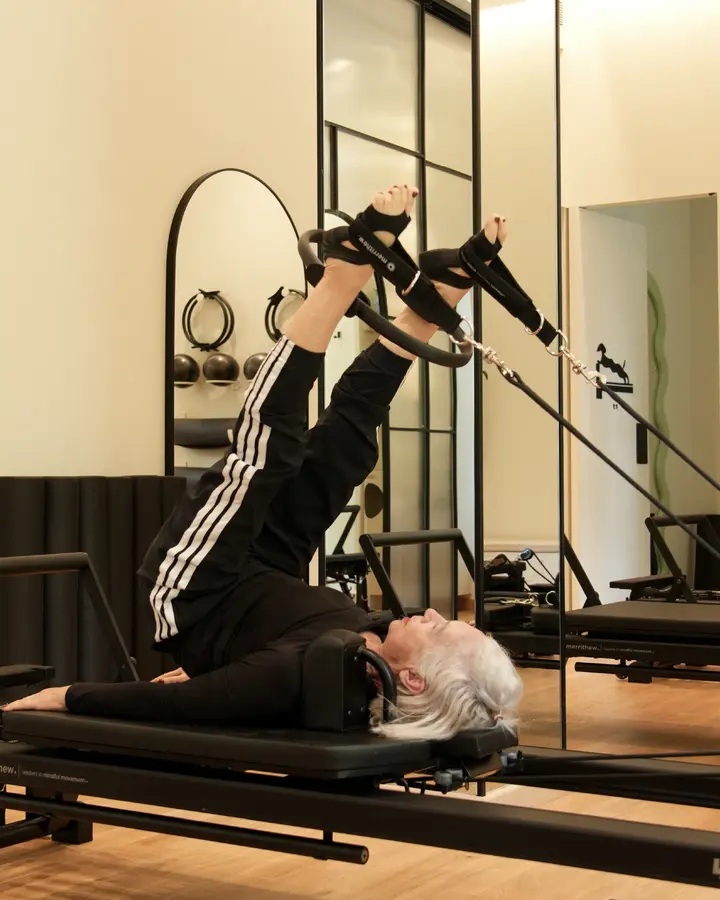 A Pilates instructor guiding a reformer stretch at Unlock Everyday